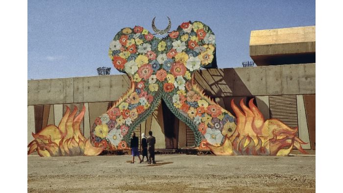 Die Außenfassade des zum Denkmal umgewandelten Bunkers mit Flammen und Blumenteppich.